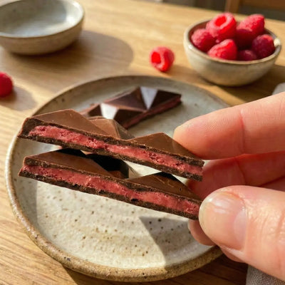 Tafel (verpackt und angeschnitten) Pink Pitaya mit dunkler Alternative zu Schokolade und gefriergetrockneter Himbeere und Drachenfrucht. Ohne Industriezucker, natürlich gesüßt, ballaststoffreich, vegan, bio.