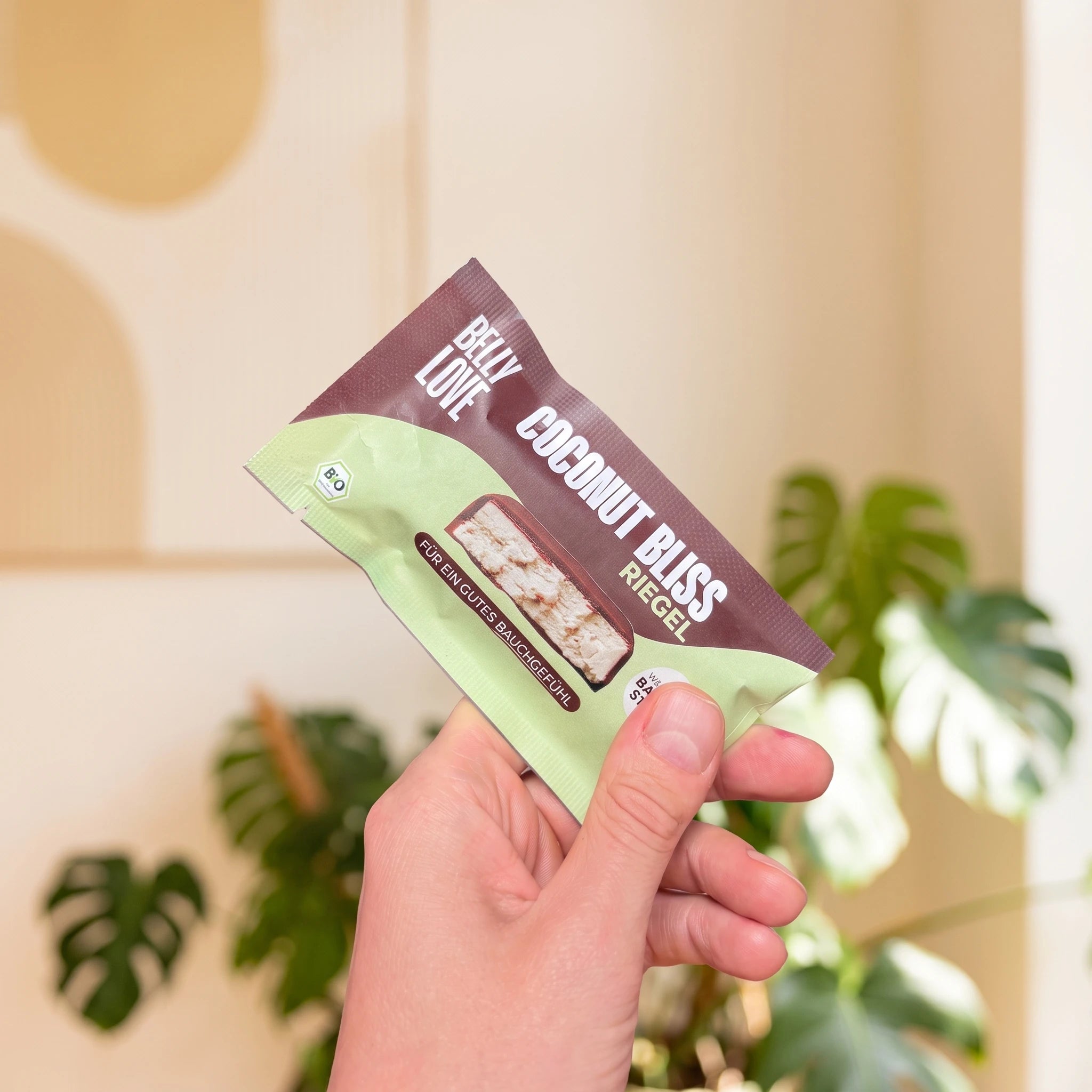 Coconut Bliss Riegel in Verpackung aus Papier in Hand