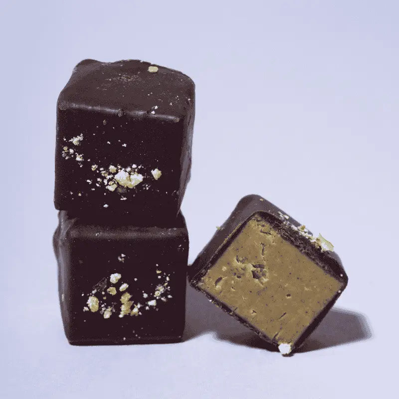 Drei Belly Love Creamy Pistachio Pralinen in Nahaufnahme – cremige Füllung mit Pistazien und Cashewmus, umhüllt von dunkler Schokolade, clean label, zuckerfrei und ballaststoffreich.