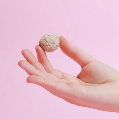 Belly Love Kokos Mandel Praline / Belly Bliss Balls mit ganzer Mandel in der Hand – äußere Hülle aus Kokosraspeln ohne Industriezucker, cremig